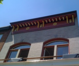 The corbels were painted in soft yellow on top of a terra cotta background. Other wood trim was painted a dark raisin. The terra cotta was selected to compliment the color of the brick on the neighboring building to the west and the firehouse to the east.